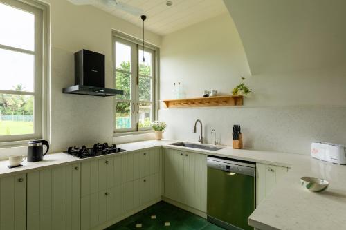 a kitchen with white cabinets and a green sink at La Rozalia, Exquisite 4 BHK Villas with Large Pool, Garden, Dedicated Caretaker, Terrace, 2 mins from the famous Dear Zindagi Road in Mapusa