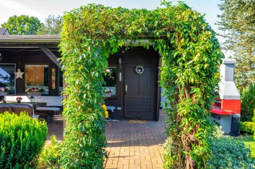 an arch covered in green ivy in front of a house at Ferienbungalow Poppengrün in Poppengrün