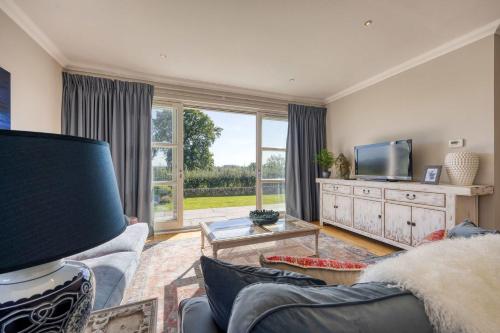 a living room with a couch and a tv at Stunning 4 Bedroom Farmhouse in Bishopton