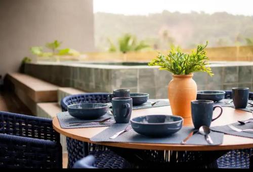 ein Holztisch mit blauen Schüsseln und einer Vase darauf in der Unterkunft Vista Milagres in São Miguel dos Milagres