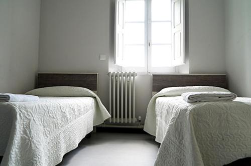 a room with two beds and a window at Albergue Capuchinos Rocamador in Estella