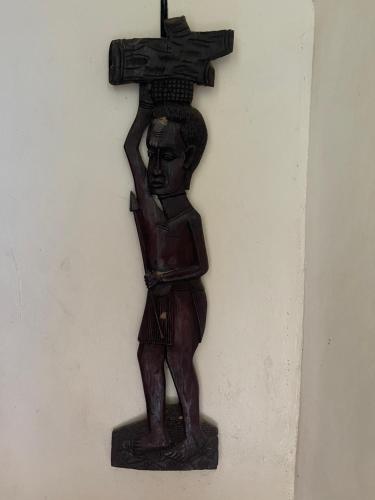 a statue of a man holding a cross on a wall at Tinka,s Homestead in Fort Portal