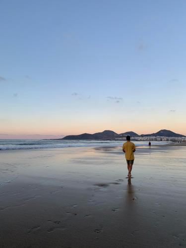 a man walking on the beach at sunset at The Wave Temple II in Las Palmas de Gran Canaria