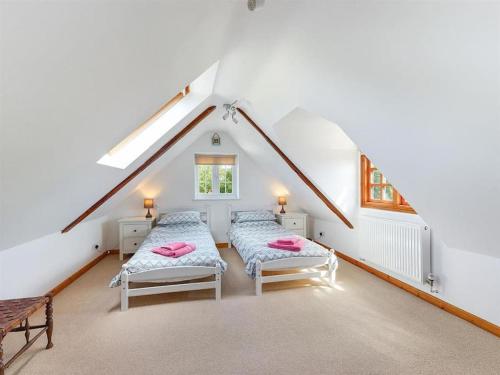 a attic room with two beds and a bench at Riverside Cottage with balcony and fishing jetty in Upton upon Severn