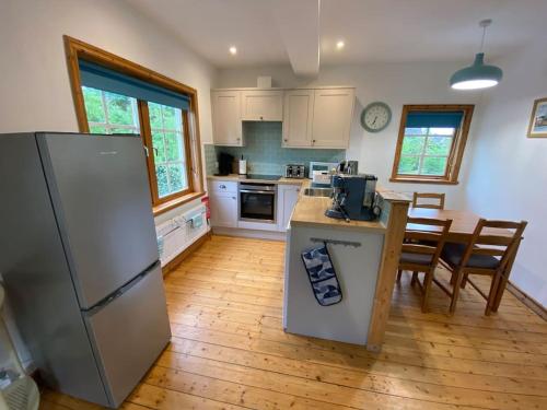 a kitchen with a refrigerator and a table with chairs at Riverside Cottage with balcony and fishing jetty in Upton upon Severn