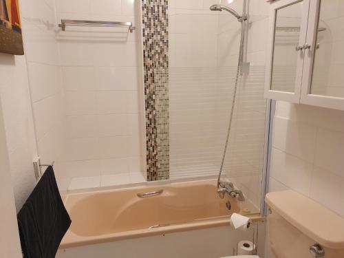 a bathroom with a tub with a shower and a toilet at Great for town & beach in Bournemouth