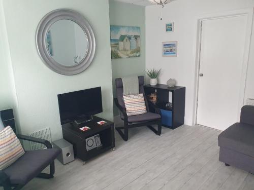 a living room with a tv and chairs and a mirror at Great for town & beach in Bournemouth