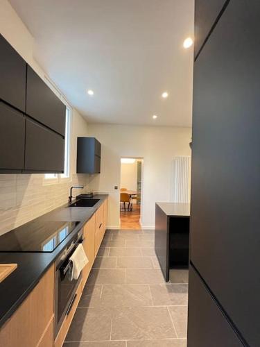 une grande cuisine avec des comptoirs et des appareils noirs dans l'établissement Hyper centre st Germain en laye appt de standing, à Saint-Germain-en-Laye