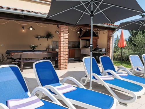 a group of chairs and an umbrella on a patio at Holiday Home Mariva by Interhome in Potpićan