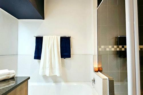 bagno con vasca, doccia e asciugamani blu di Herolds Bay 510 a Herolds Bay