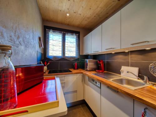 une cuisine avec des placards blancs et un comptoir rouge dans l'établissement Apartment La Lauze by Interhome, à La Toussuire