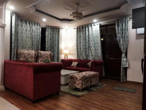 a living room with two red chairs and a door at Antara - A Boutique Villa By Shivaneel Hospitality, Chail in Chail