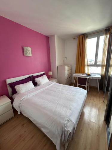une chambre avec un lit blanc et un mur rose dans l'établissement Superbe appartement vue sur la Seine situé à Boulogne-Billancourt, à Boulogne-Billancourt