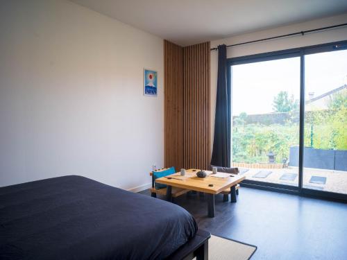 a bedroom with a bed and a table and a large window at Kitsuné Lodge zen d'inspiration japonaise in Chaintré