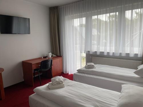 a hotel room with two beds and a desk and a television at Nadmorski in Mrzeżyno