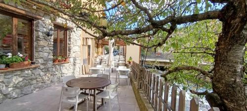 a patio with a table and chairs and a tree at Hotel Saurat in Espot