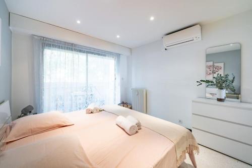 - une chambre blanche avec un grand lit et des serviettes dans l'établissement Croisette vue mer 2 pièces, à Cannes