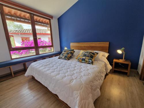 a blue bedroom with a bed with pillows and a window at Hotel La Caracola Salento in Salento