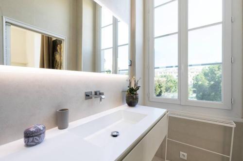 une salle de bain blanche avec un lavabo et un miroir dans l'établissement Le Massena, à Nice