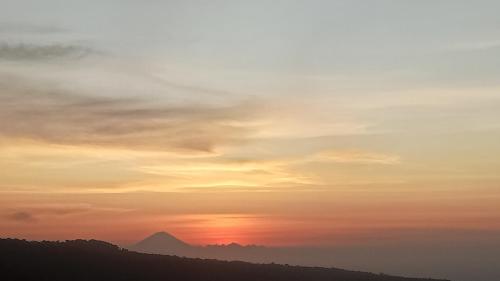 a sunset with a mountain in the background at Senaru sunset house in Senaru