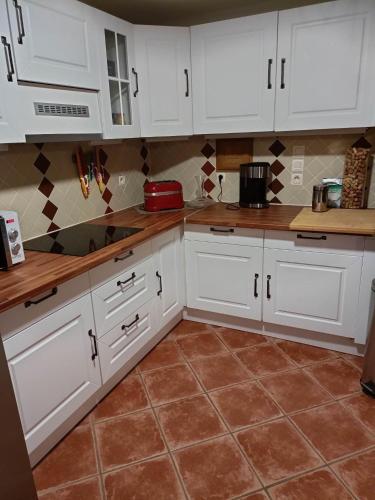 une cuisine avec des armoires blanches et un sol carrelé dans l'établissement Longère de charme entre campagne et mer, à Hermival-les-Vaux