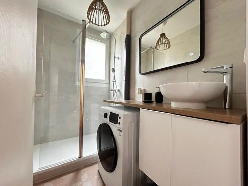 une salle de bain avec une machine à laver et un lavabo dans l'établissement Le Limousin, authentique avec balcons, à Limoges