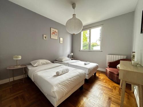 une chambre avec deux lits et une fenêtre dans l'établissement Le Limousin, authentique avec balcons, à Limoges