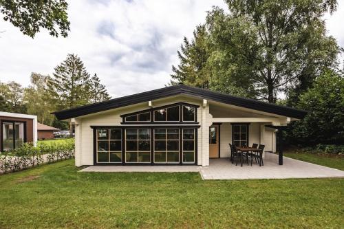 a small white house with black windows at Houten chalet 'De Blokhut' in Voorthuizen