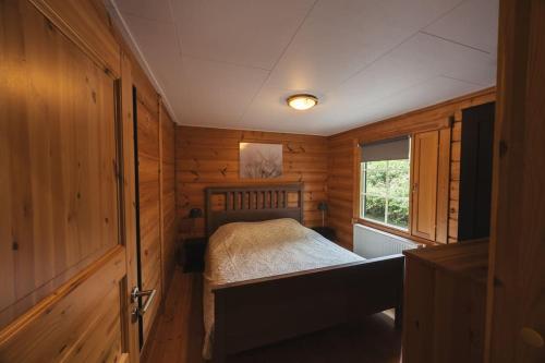 a small bedroom with a bed in a wooden cabin at Houten chalet 'De Blokhut' in Voorthuizen