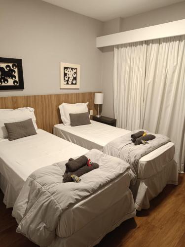 two beds in a hotel room with stuffed animals on them at H4 La Residence Paulista in Sao Paulo