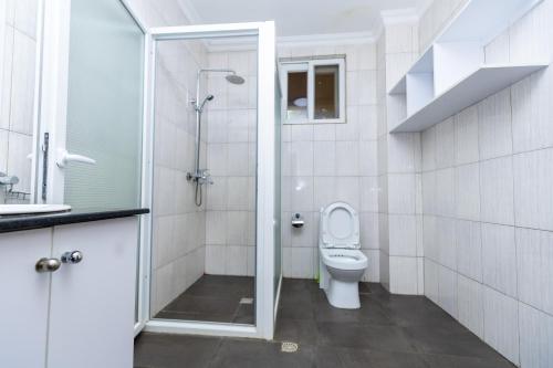 a bathroom with a toilet and a glass shower at Hotappa Suite Apartment in Kigali