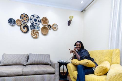 a woman sitting on a couch in a living room at Hotappa Suite Apartment in Kigali