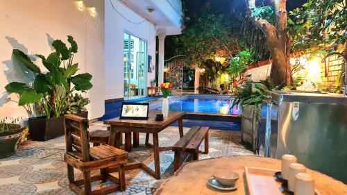 a patio with a table and chairs and a pool at Minh Trang Villa Hoi An -BBQ Garden in Hoi An