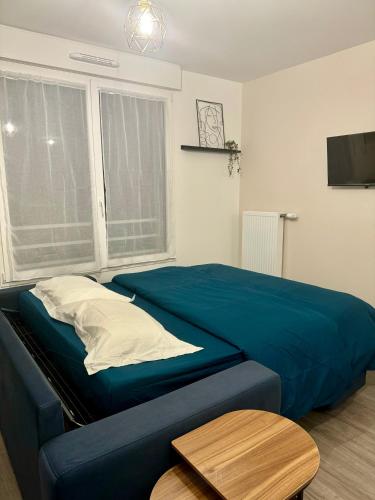 - une chambre avec un lit bleu et une table dans l'établissement Studio moderne et tout équipé, proche du RER, Paris & aéroport d'Orly en 20 min, lit bébé sur demande, à Vitry-sur-Seine