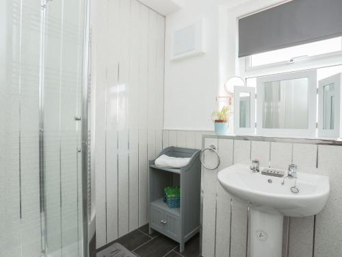 a white bathroom with a sink and a shower at Wave from it All in Llandudno