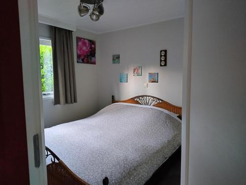 a bedroom with a bed with white sheets and a window at Vakantie chalet Utrechtse Heuvelrug in Overberg