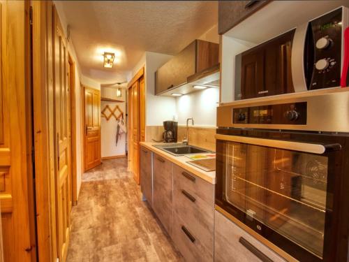 une cuisine avec des armoires en bois et un four à plaques de cuisson dans l'établissement Charmant appart 6 pers, proche lac et navette - FR-1-642-17, à Morillon