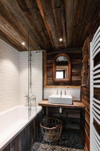 une salle de bain avec un lavabo, une baignoire et un miroir dans l'établissement Le Ruisseau, Lindarets, authentique, 11 personnes, à Montriond
