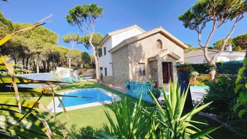 ein altes Steinhaus mit Pool und Bäumen in der Unterkunft Villa Zahara in Chiclana de la Frontera