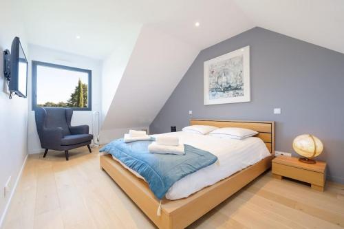 a bedroom with a large bed and a chair at Villa, piscine intérieure - Baie Mont Saint Michel in Le Petit-Celland