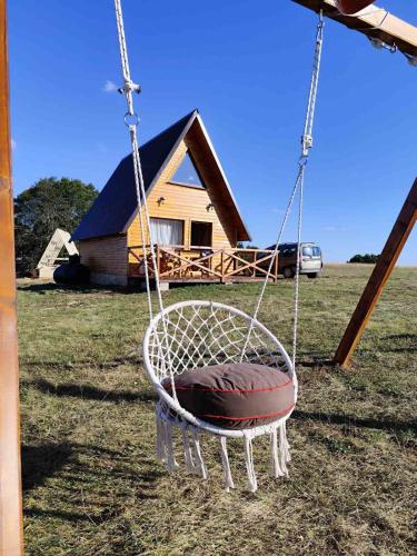 a swing in a field with a house in the background at The View Smrcevo Brdo in Žabljak