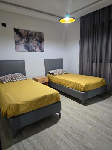 two beds in a room with yellow sheets at Luxury apartment in Ariana