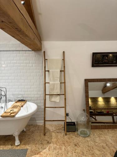La salle de bains est pourvue d'une baignoire blanche, d'une échelle et d'un miroir. dans l'établissement Magnifique et confortable loft, à Marlieux