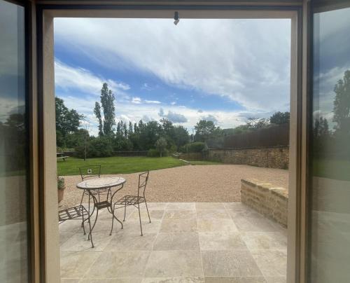 Blick auf eine Terrasse mit einem Tisch und Stühlen in der Unterkunft L'Oxalis doré in Frontenas