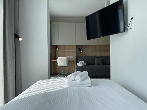 a bedroom with a bed with towels and a flat screen tv at Wilanów Residence Apartments in Warsaw