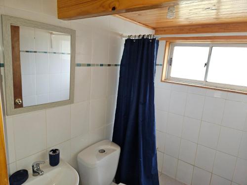 a bathroom with a blue shower curtain and a toilet at Linda Cabaña con Vista al Mar a Pasos de la Playa in La Ligua