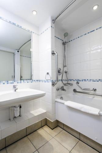 a bathroom with a sink and a tub and a mirror at Holiday Inn Milton Keynes Central by IHG in Milton Keynes