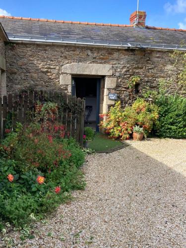a stone house with a doorway and flowers in front of it at Gîte la peille in Cordemais
