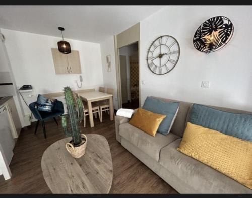 un salon avec un canapé et une horloge au mur dans l'établissement Le cannois, à Cannes