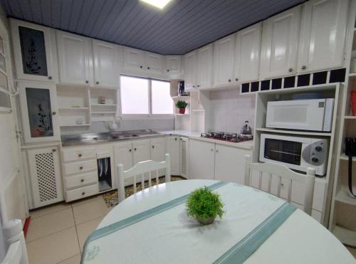 a kitchen with white cabinets and a table with a plant on it at Apartamento London - Centro Nova Petrópolis in Nova Petrópolis